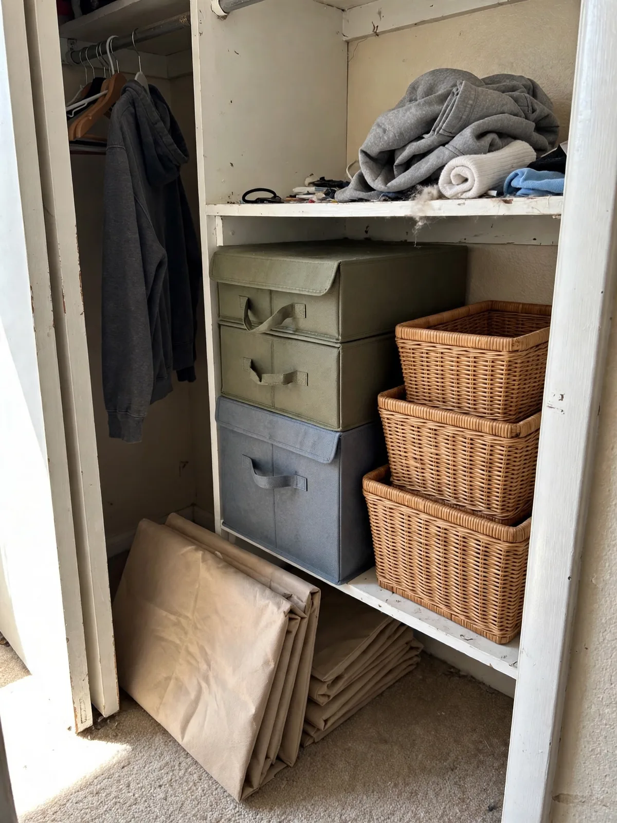 Foldable fabric storage boxes and nesting baskets stacked in a small apartment closet, a few folded flat beside the stack