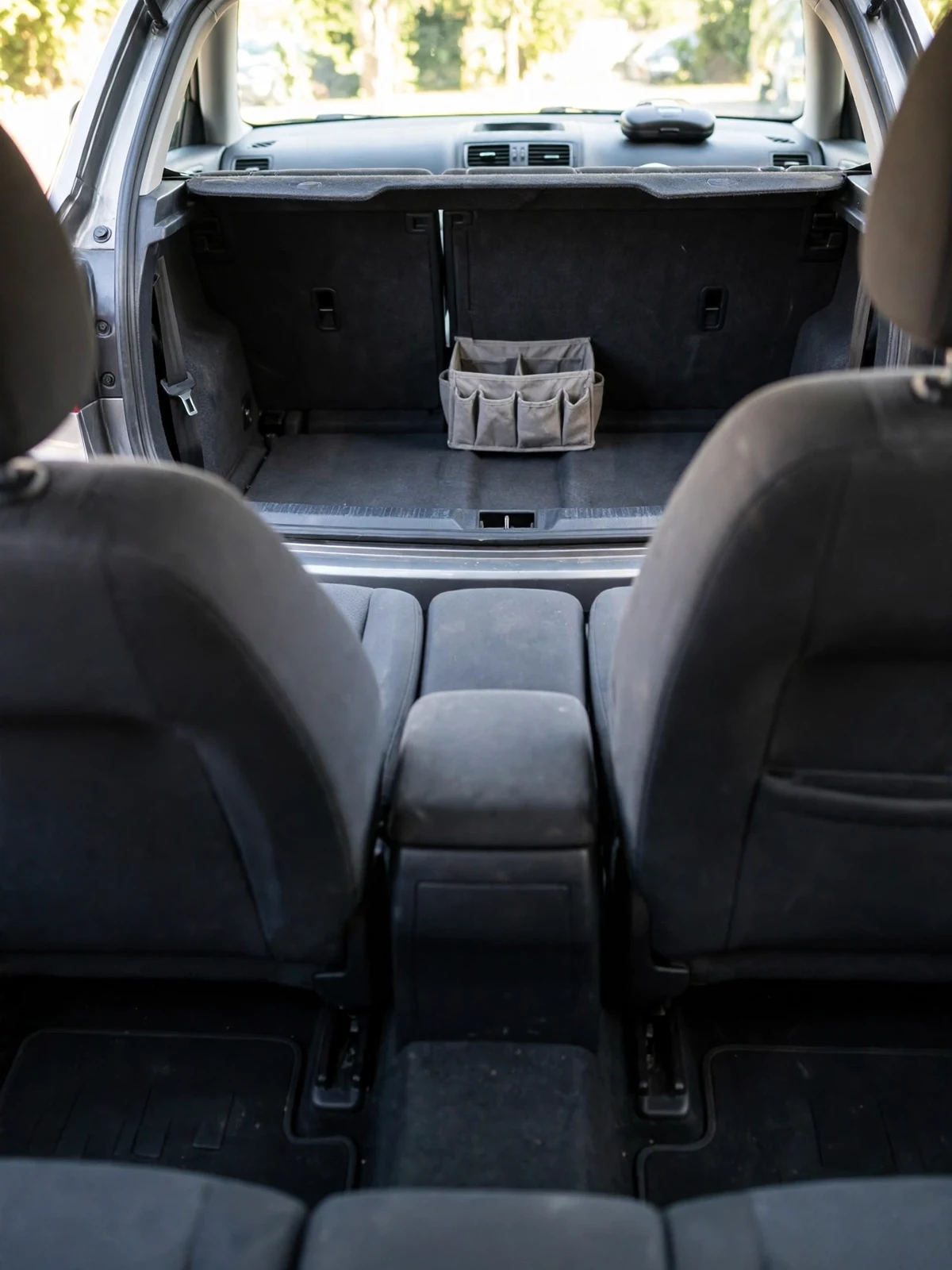 The tidy interior of a family car viewed from the back seat, with clean seats and a small organiser in the empty boot