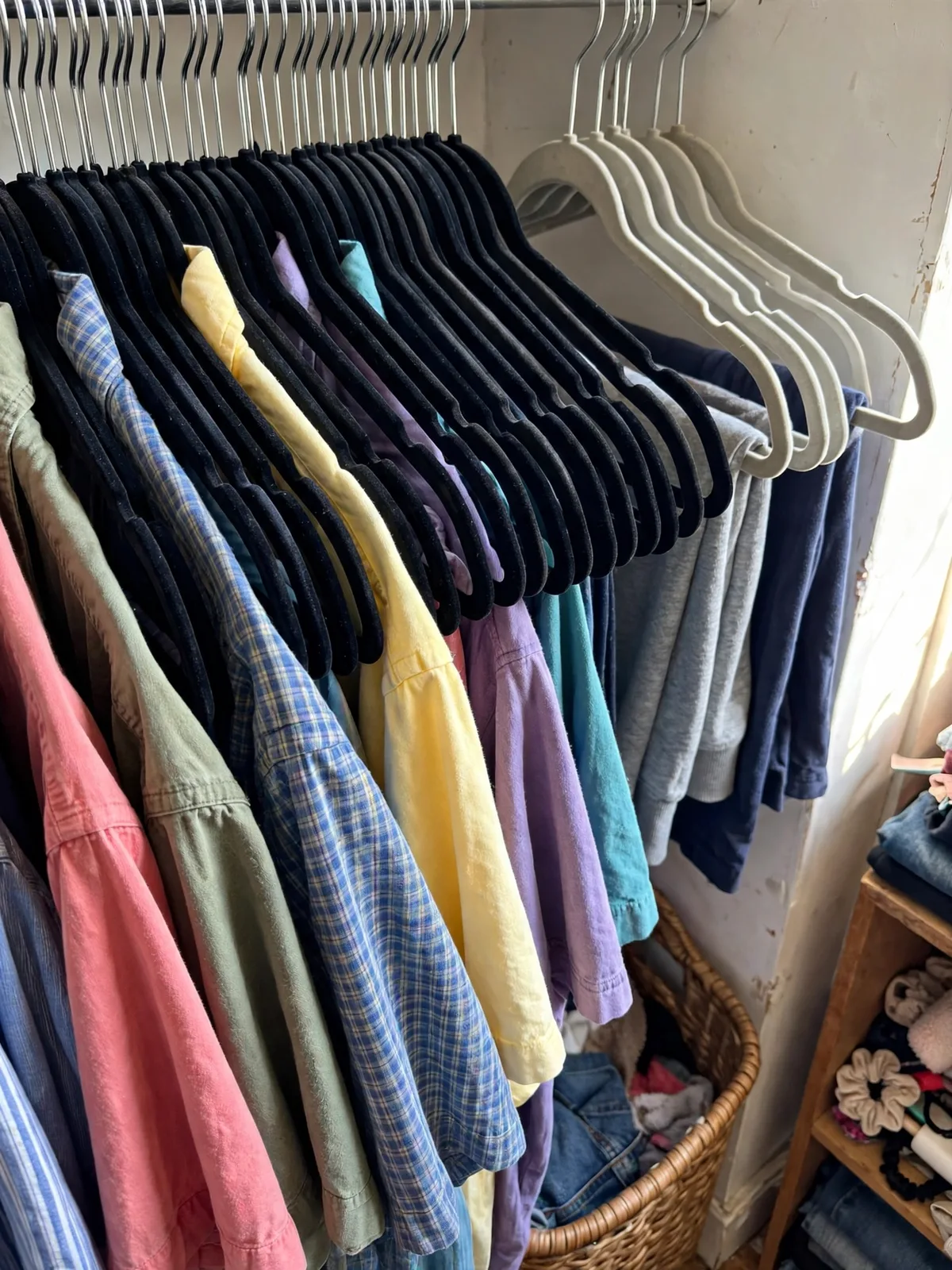 Slim velvet hangers packed tightly on a garment rack holding shirts, saving space compared with bulky hangers